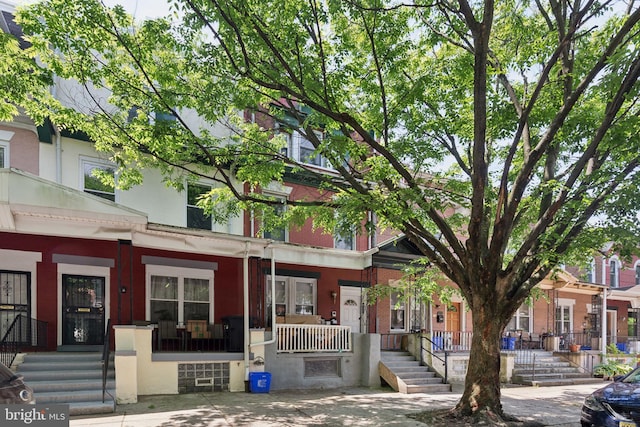 townhome / multi-family property with covered porch and brick siding