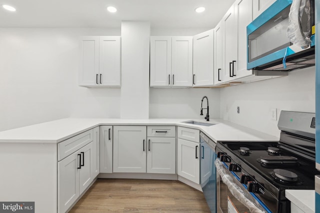 kitchen featuring white cabinets, stainless steel appliances, light countertops, light wood-style floors, and a sink