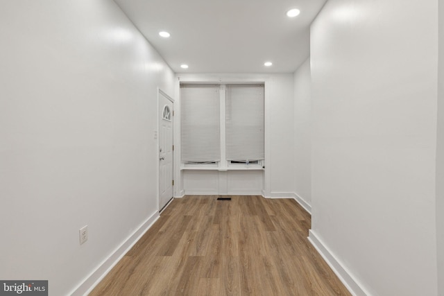 hallway with recessed lighting, wood finished floors, visible vents, and baseboards