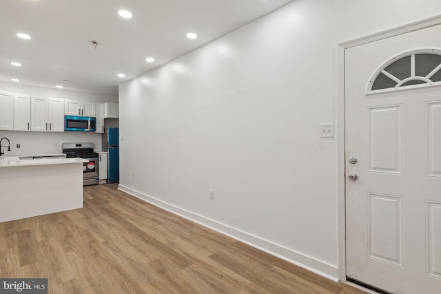 kitchen featuring recessed lighting, white cabinetry, light countertops, appliances with stainless steel finishes, and light wood finished floors