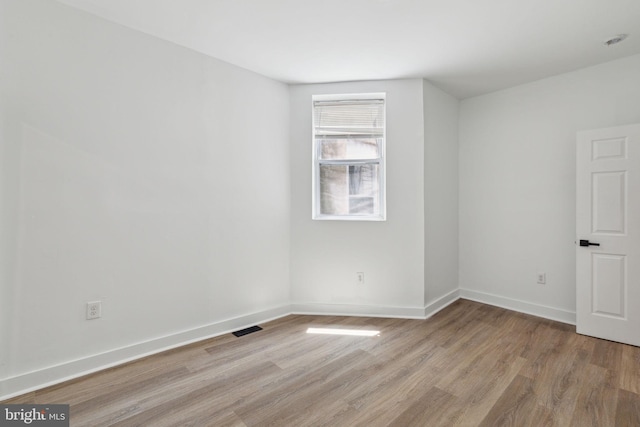 empty room featuring visible vents, light wood-style flooring, and baseboards