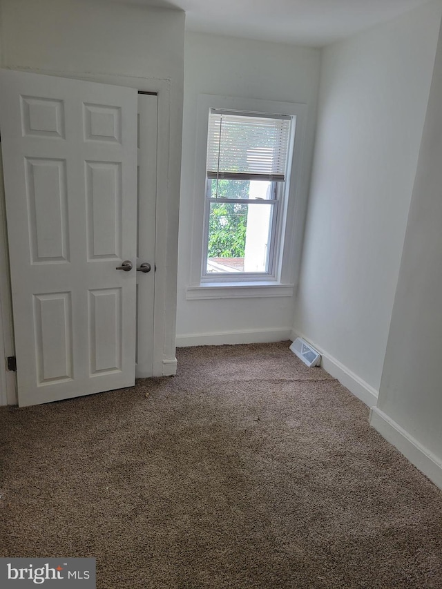 empty room with baseboards, visible vents, and carpet flooring