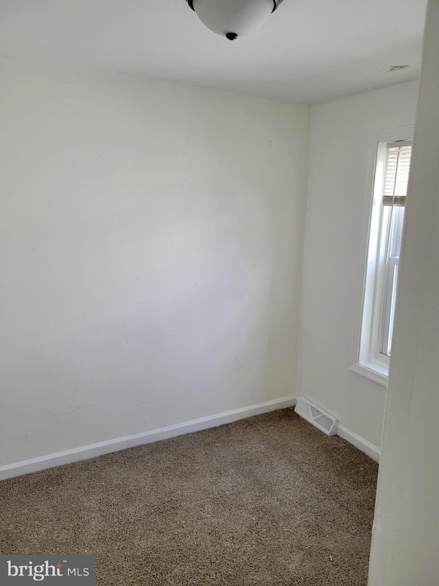 carpeted empty room featuring baseboards and visible vents