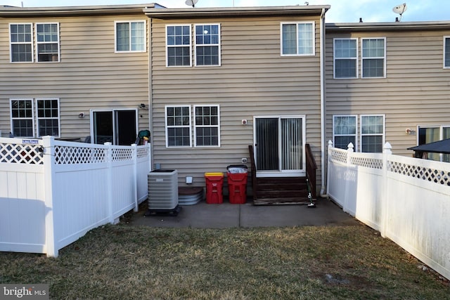 back of house featuring entry steps, a yard, central AC unit, and a fenced backyard