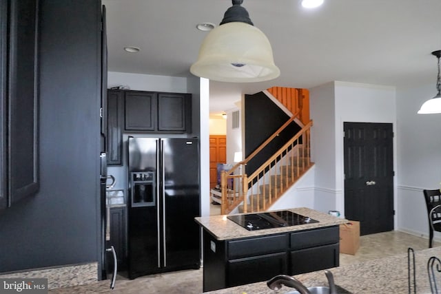 kitchen with pendant lighting, black appliances, light stone counters, and dark cabinets