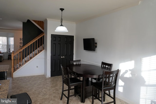 dining room featuring ornamental molding and stairway