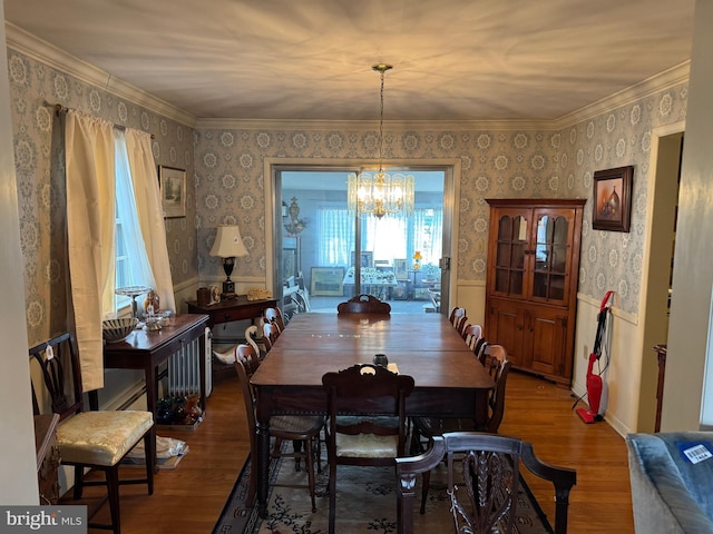 dining space with wood finished floors, wainscoting, and wallpapered walls