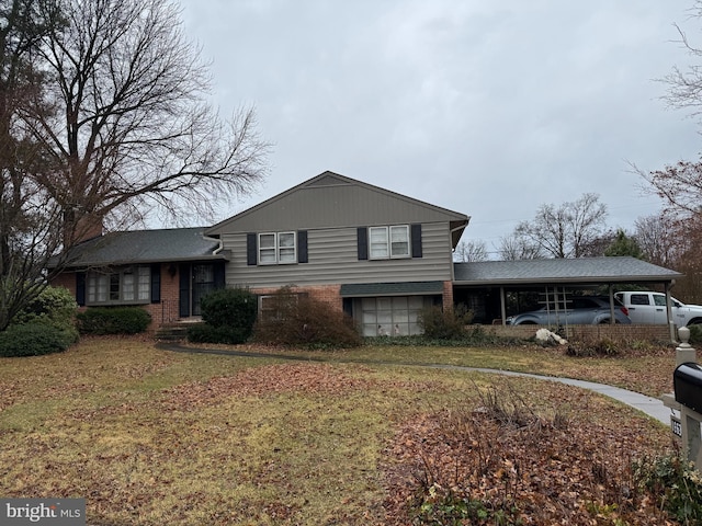 split level home featuring a carport, brick siding, and a front lawn