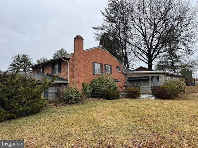 view of home's exterior with brick siding, a chimney, and a lawn