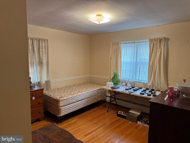 bedroom featuring a baseboard heating unit and wood finished floors