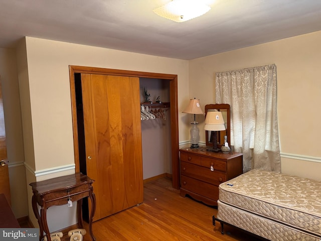 bedroom featuring wood finished floors, a closet, and baseboards