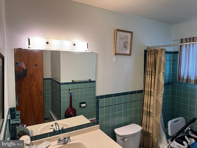 bathroom featuring wainscoting, vanity, toilet, and tile walls