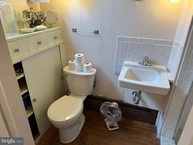 bathroom with toilet, wood finished floors, and a sink