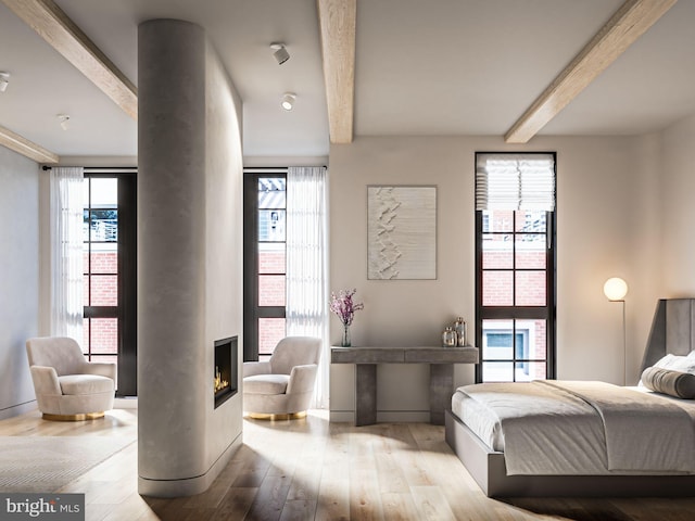 bedroom featuring beam ceiling, a fireplace, and wood finished floors