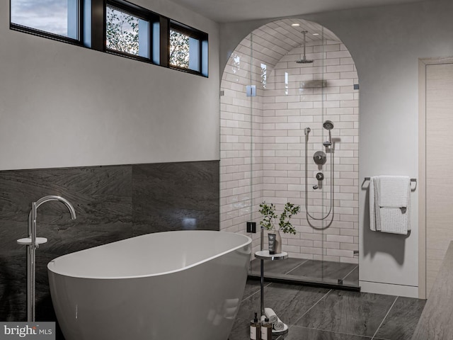 bathroom featuring a stall shower, a freestanding tub, and tile walls