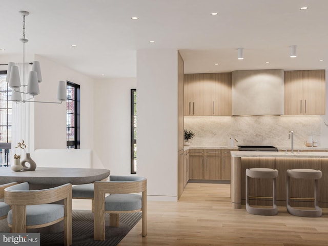 kitchen with wall chimney exhaust hood, modern cabinets, light brown cabinets, and light wood-style flooring