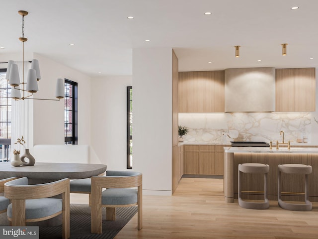 kitchen with light brown cabinets, light wood-style floors, light countertops, backsplash, and modern cabinets