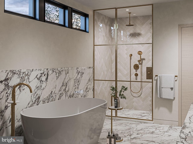 bathroom featuring a soaking tub, marble finish floor, a tile shower, and tile walls