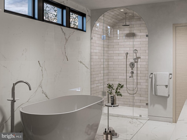 bathroom featuring marble finish floor, a freestanding tub, and a shower stall