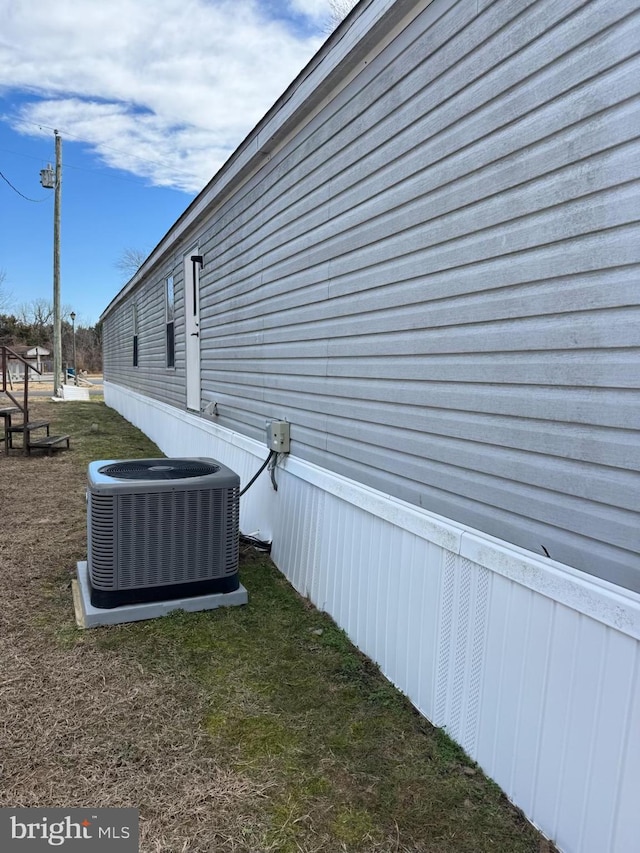 view of side of home featuring a lawn and cooling unit