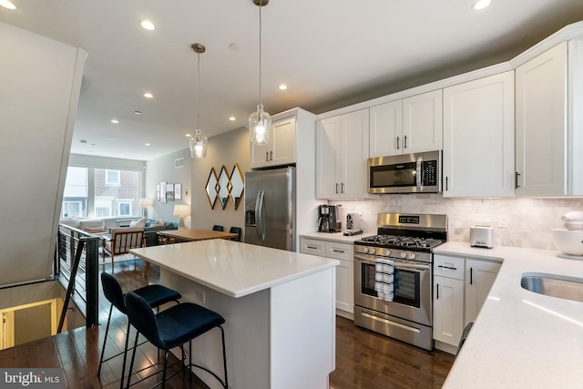 kitchen with tasteful backsplash, a kitchen island, dark wood finished floors, recessed lighting, and appliances with stainless steel finishes