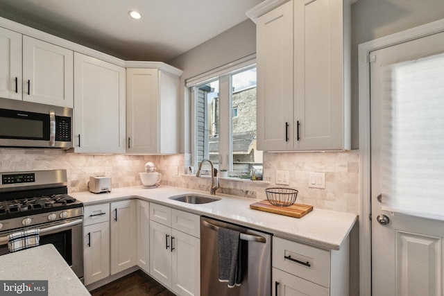 kitchen with a sink, tasteful backsplash, appliances with stainless steel finishes, and white cabinetry