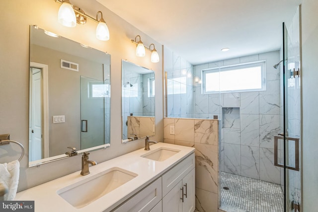 bathroom with double vanity, visible vents, a marble finish shower, and a sink