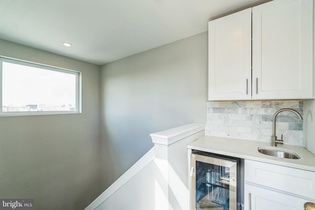 bar featuring beverage cooler, backsplash, wet bar, and a sink