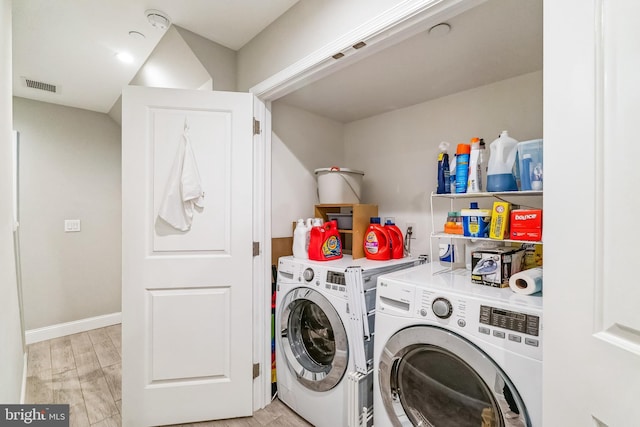 washroom with visible vents, light wood-style floors, baseboards, laundry area, and washing machine and clothes dryer