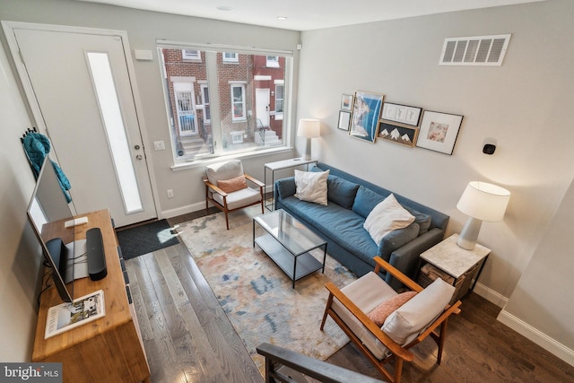 living area featuring visible vents, baseboards, and wood finished floors