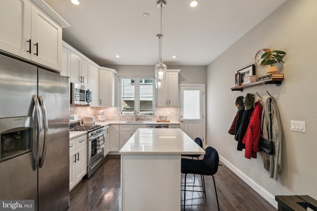 kitchen with a kitchen bar, backsplash, appliances with stainless steel finishes, white cabinets, and light countertops