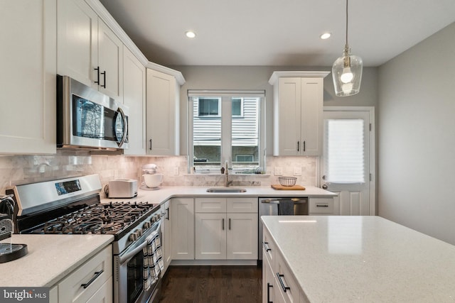 kitchen with a sink, decorative light fixtures, tasteful backsplash, white cabinetry, and appliances with stainless steel finishes