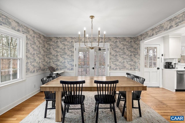 dining room with light wood-style flooring, french doors, wainscoting, wallpapered walls, and crown molding