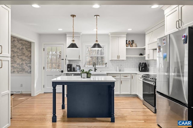 kitchen with stainless steel appliances, light countertops, light wood-type flooring, open shelves, and a sink