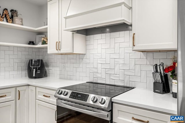 kitchen featuring stainless steel range with electric stovetop, premium range hood, white cabinetry, and open shelves