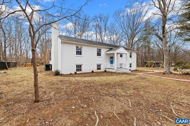 view of front of home with a chimney, central AC unit, and brick siding