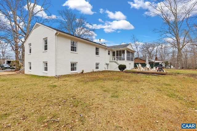 back of house with a sunroom, a lawn, and a wooden deck