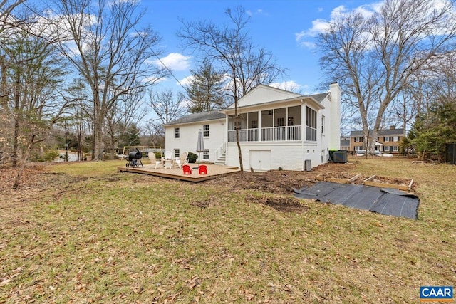 rear view of property with a yard, a chimney, central air condition unit, a sunroom, and a wooden deck