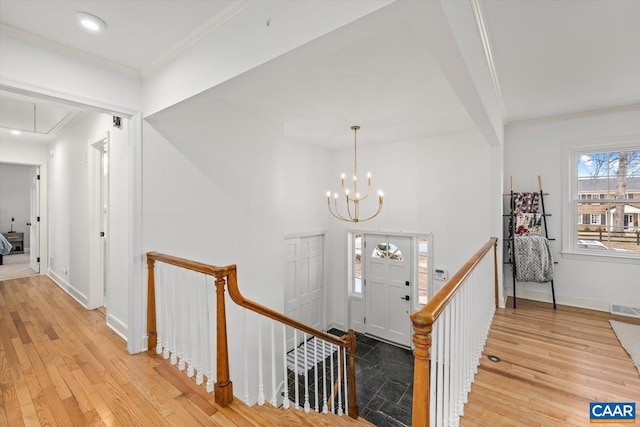 interior space with attic access, ornamental molding, light wood-style flooring, and an upstairs landing