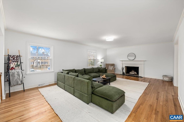 living room with ornamental molding, visible vents, and light wood-style floors