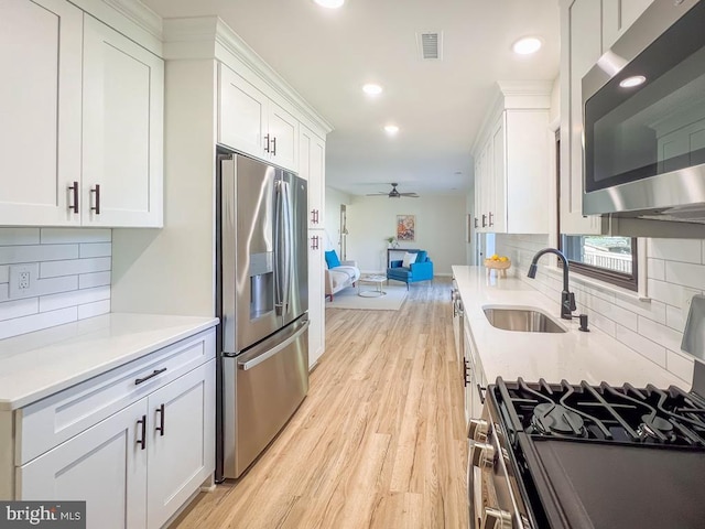 kitchen with stainless steel appliances, a sink, visible vents, white cabinetry, and open floor plan