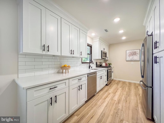 kitchen with stainless steel appliances, tasteful backsplash, visible vents, white cabinetry, and a sink