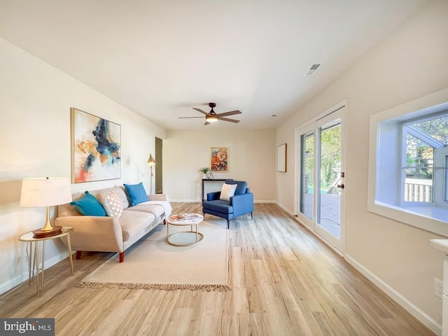 living area featuring visible vents, ceiling fan, baseboards, and wood finished floors