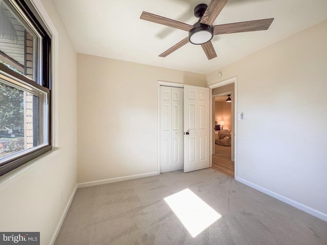 unfurnished bedroom featuring a closet, carpet flooring, a ceiling fan, and baseboards