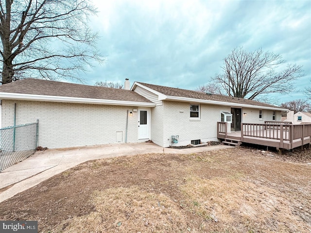 back of property featuring a chimney, roof with shingles, fence, a deck, and brick siding