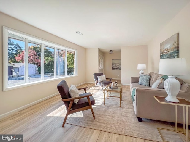 living room with visible vents, light wood-style flooring, and baseboards