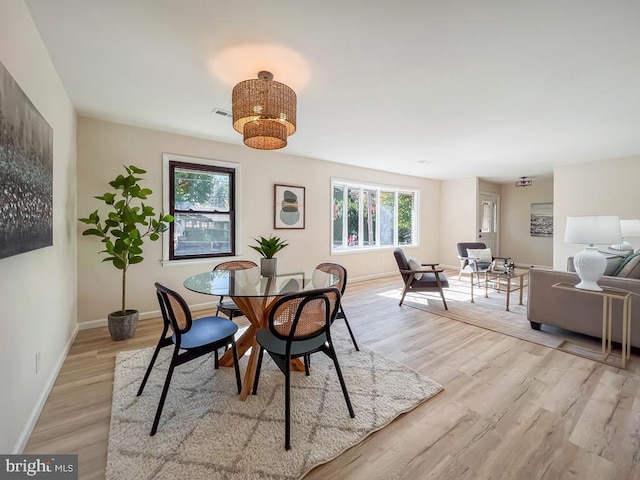 dining area with visible vents, light wood-style flooring, and baseboards