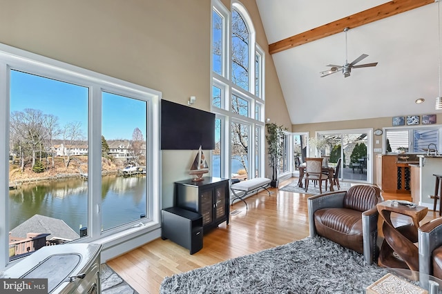 living area featuring beam ceiling, high vaulted ceiling, a ceiling fan, and wood finished floors