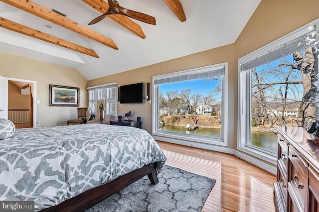 bedroom featuring light wood finished floors, visible vents, lofted ceiling with beams, and ceiling fan