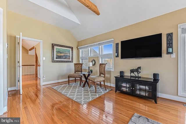 living area featuring baseboards, light wood-style floors, and vaulted ceiling